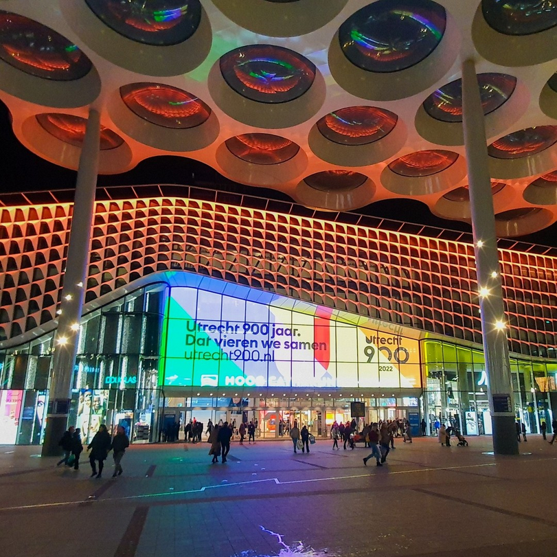 Grote schermen op Utrecht Centraal onder het Bollendak met de Zwarte tekst "Utrecht 900 jaar Dat vieren we samen." 